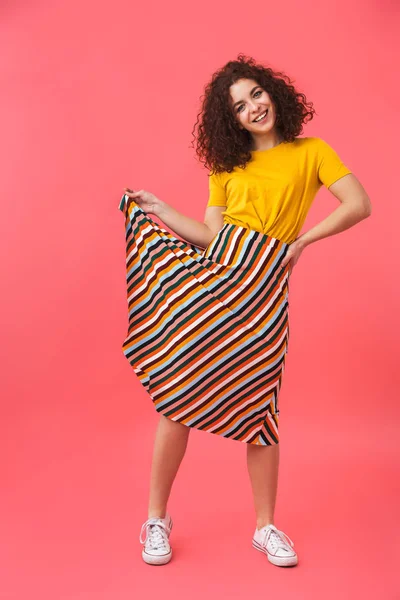 Kırmızı duvar arka plan üzerinde izole poz sevimli mutlu güzel genç kıvırcık kız.