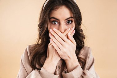 Şok genç güzel kadın ağız kapsayan bej arka plan duvardan izole poz.