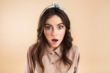 Bej renkli arka plan duvardan izole poz güzel heyecanlı sürpriz genç güzel kadın.