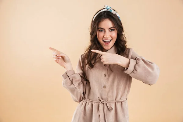 Jovem feliz posando isolado sobre fundo parede bege apontando . — Fotografia de Stock