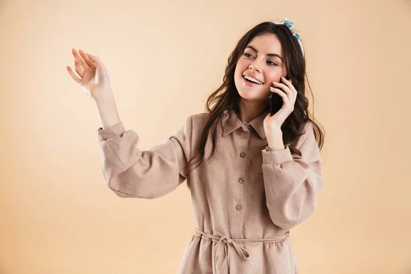 Mujer joven posando aislada sobre fondo de pared beige hablando por teléfono móvil . —  Fotos de Stock