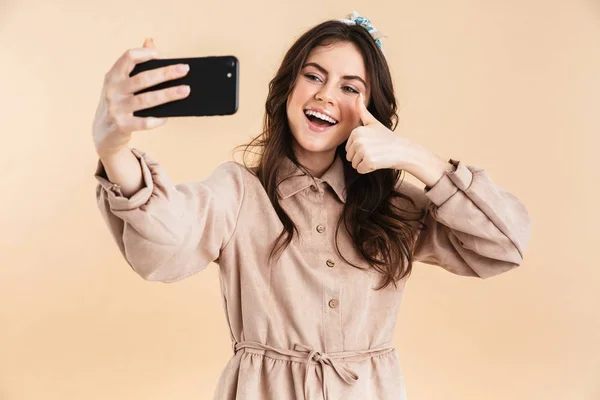 Mulher posando isolado sobre fundo de parede bege tirar selfie por telefone móvel . — Fotografia de Stock