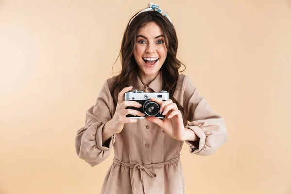 Emocionado joven mujer bonita fotógrafo posando aislado sobre fondo beige de la pared celebración de la cámara . —  Fotos de Stock