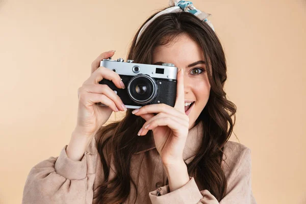 Emocionado jovem fotógrafo bonita posando isolado sobre fundo bege parede segurando câmera . — Fotografia de Stock