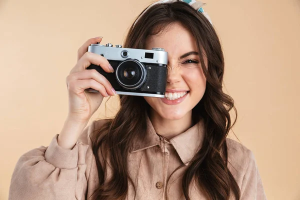 Emocionado jovem fotógrafo bonita posando isolado sobre fundo bege parede segurando câmera . — Fotografia de Stock