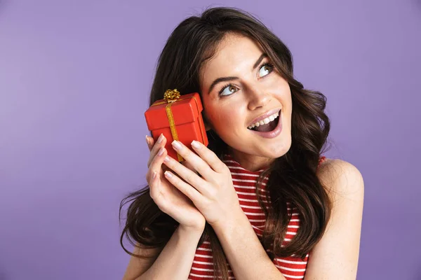 Щаслива молода красива жінка позує ізольована на фіолетовому фоні стіни тримає подарункову коробку . — стокове фото