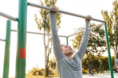 Konsantre genç sporcu barlar üzerinde egzersizleri yapıyor