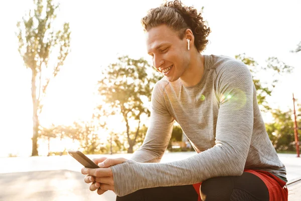 Deportista seguro con auriculares sentados al aire libre — Foto de Stock