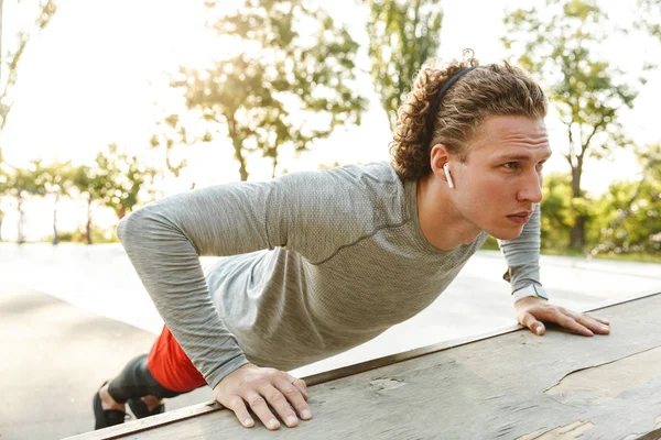 Jovem desportista confiante fazendo exercícios ao ar livre — Fotografia de Stock