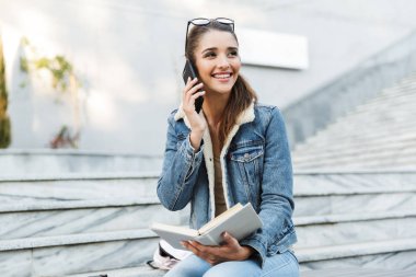 Bir bankta oturan ceket giyen gülümseyen genç kadın