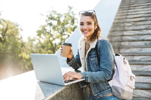 Mujer joven sonriente con chaqueta sentada en un banco —  Fotos de Stock