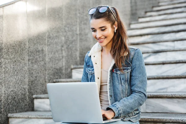 Mujer joven sonriente con chaqueta sentada en un banco —  Fotos de Stock