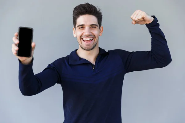 Joven alegre mostrando la pantalla en blanco del teléfono móvil — Foto de Stock