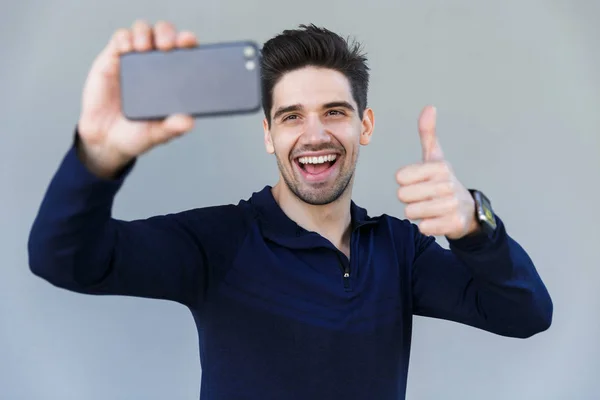 Wesoły młody człowiek biorąc selfie na białym tle — Zdjęcie stockowe