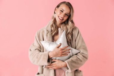 Güzel kadın pembe duvar arka plan tutan yastık yıldız üzerinde izole poz.