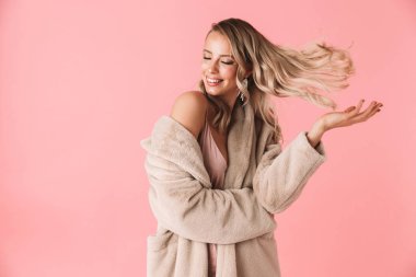 Güzel kadın moda ceket giymiş pembe duvar arka plan üzerinde izole poz.