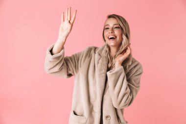 Güzel kadın arkadaş sallayarak moda ceket giymiş pembe duvar arka plan üzerinde izole poz.