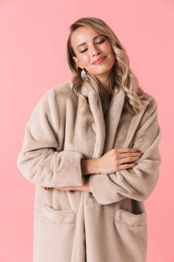 Güzel kadın moda ceket giymiş pembe duvar arka plan üzerinde izole poz.