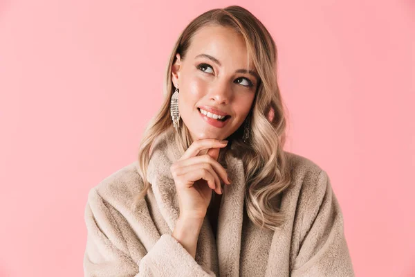 Mooie vrouw poseren geïsoleerd over roze muur achtergrond gekleed in de mode jas. — Stockfoto