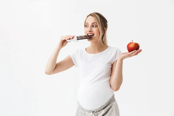 Mooie zwangere vrouw Holding chocolade bar en rode appel — Stockfoto