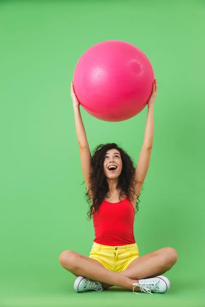 Bild einer hübschen Frau, die mit Fitnessball auf dem Boden sitzt — Stockfoto