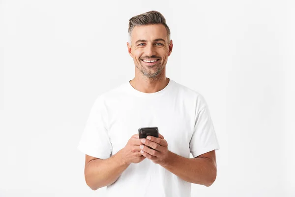 Imagen del hombre alegre de 30 años con camiseta casual sosteniendo y usi — Foto de Stock