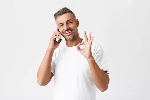 Imagen del hombre optimista de 30 años con camiseta casual sosteniendo inteligente —  Fotos de Stock