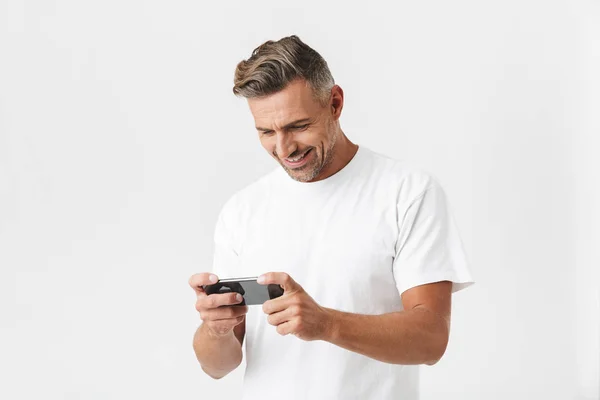 Imagen de un hombre positivo de 30 años usando una camiseta casual usando smartphon — Foto de Stock