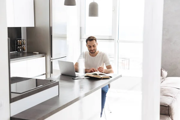 Schöner junger Mann, der zu Hause am Laptop arbeitet — Stockfoto