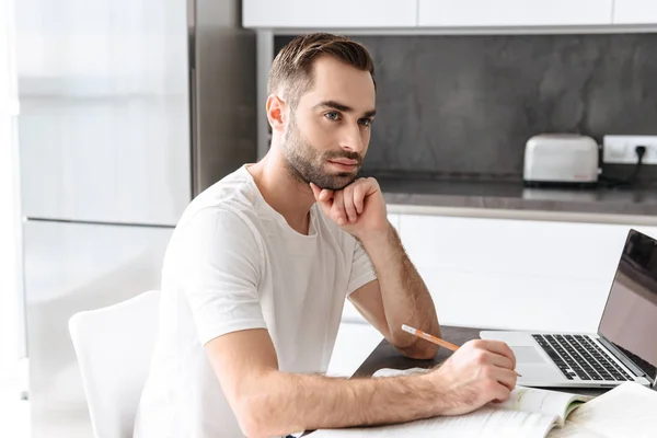 Snygg ung man som arbetar på bärbar dator hemma — Stockfoto