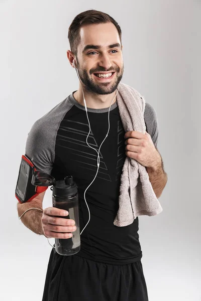 Bonito jovem esportes fitness homem posando isolar sobre fundo da parede branca ouvir música com fones de ouvido . — Fotografia de Stock