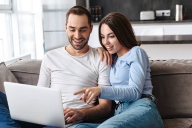 SOF üzerinde otururken birlikte laptop kullanarak mutlu çift görüntü