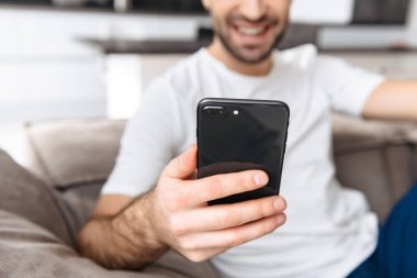 Evde bir kanepede oturan gülümseyen genç adam