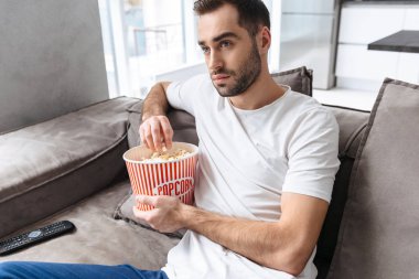 Evde bir kanepede oturan yakışıklı genç adam