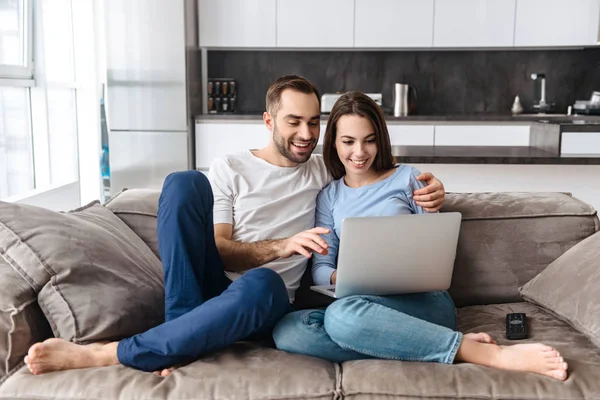 Imagen de pareja caucásica usando el ordenador portátil mientras están sentados en —  Fotos de Stock