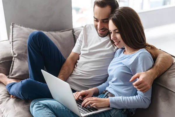 Imagen de pareja optimista usando el portátil juntos mientras están sentados o — Foto de Stock