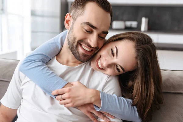 Image of couple in love hugging together at home while sitting o — Stock Photo, Image