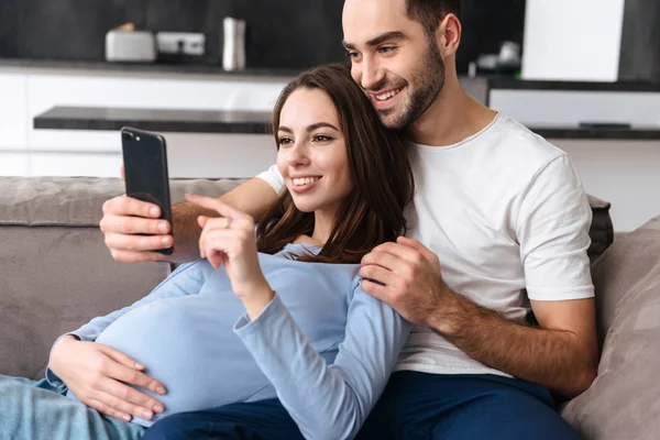 Beeld van de Europese zwangere vrouw en knappe man liggend op sofa — Stockfoto