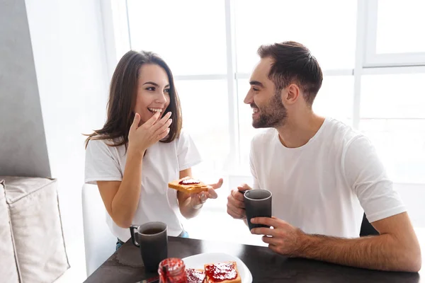 Portait de alegre pareja desayunando en casa y comiendo toa — Foto de Stock
