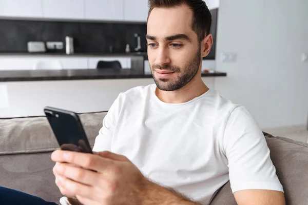 Joven sonriente sentado en un sofá en casa — Foto de Stock