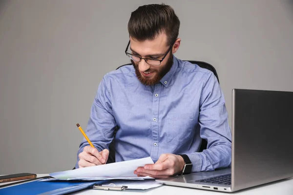 Tevreden bebaarde elegante mens in oogglazen die iets schrijven — Stockfoto