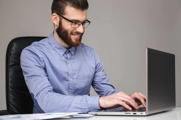 Lächelnder eleganter Mann mit Brille tippt etwas in Laptop-Computer — Stockfoto