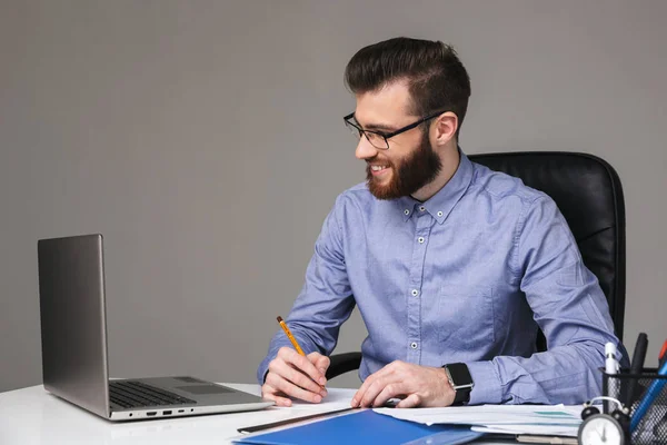 Uomo elegante barbuto sorridente in occhiali da vista utilizzando computer portatile — Foto Stock