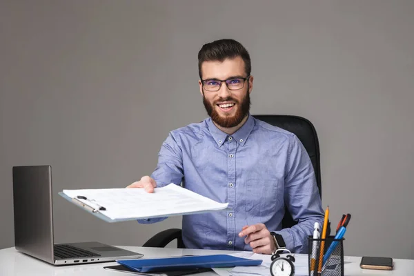 Smiling bearded elegant man in eyeglasses giving clipboard at camera — Stock Photo, Image