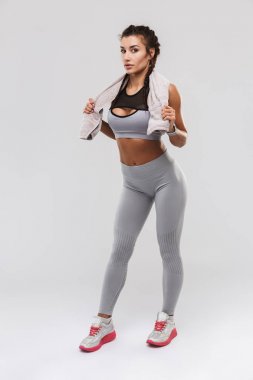 Güzel genç inanılmaz güçlü spor fitness kadın beyaz duvar arka plan havlu tutarak üzerinde izole poz.