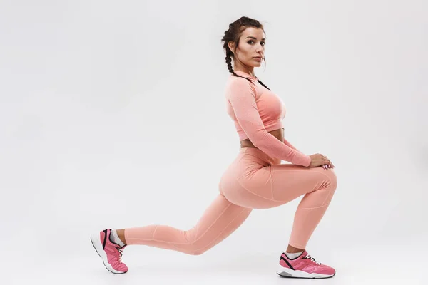 Joven increíble deporte fuerte fitness mujer posando aislado sobre fondo blanco de la pared hacer ejercicios . — Foto de Stock