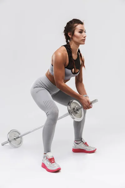 Jovem incrível forte esportes fitness mulher posando isolado sobre fundo da parede branca fazer exercícios com barra . — Fotografia de Stock