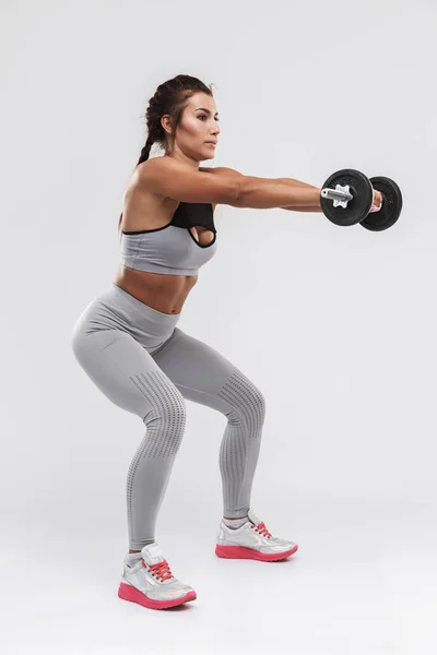 Wanita cantik dengan kebugaran olahraga yang kuat yang berpose terisolasi di atas latar belakang dinding putih membuat latihan dengan dumbbell . — Stok Foto