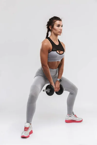 Bonito jovem incrível forte esportes fitness mulher posando isolado sobre fundo de parede branca fazer exercícios com haltere . — Fotografia de Stock