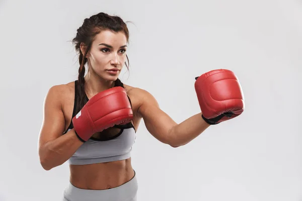 Hermosa joven increíble deporte fuerte fitness mujer boxeador posando aislado sobre fondo de pared blanca hacer ejercicios con guantes . — Foto de Stock